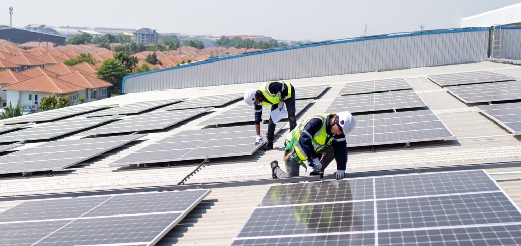 Engineer on rooftop kneeling next to solar panels photo voltaic with tool in hand for installation